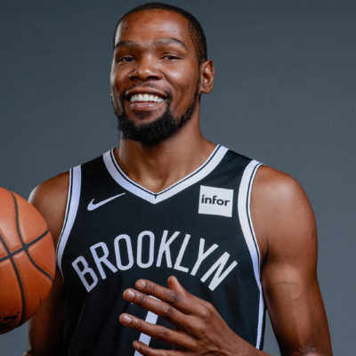 Kevin Durant holding a basketball and smiling because the Nets love NYC.