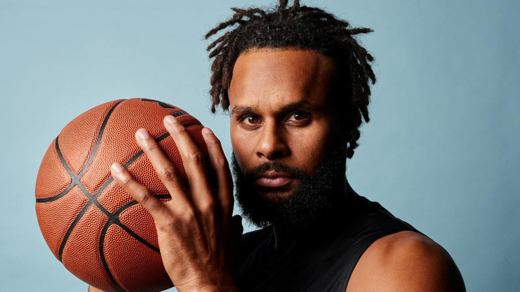 Basketball player Patty Mills holding a basketball showing that the Nets love NYC.